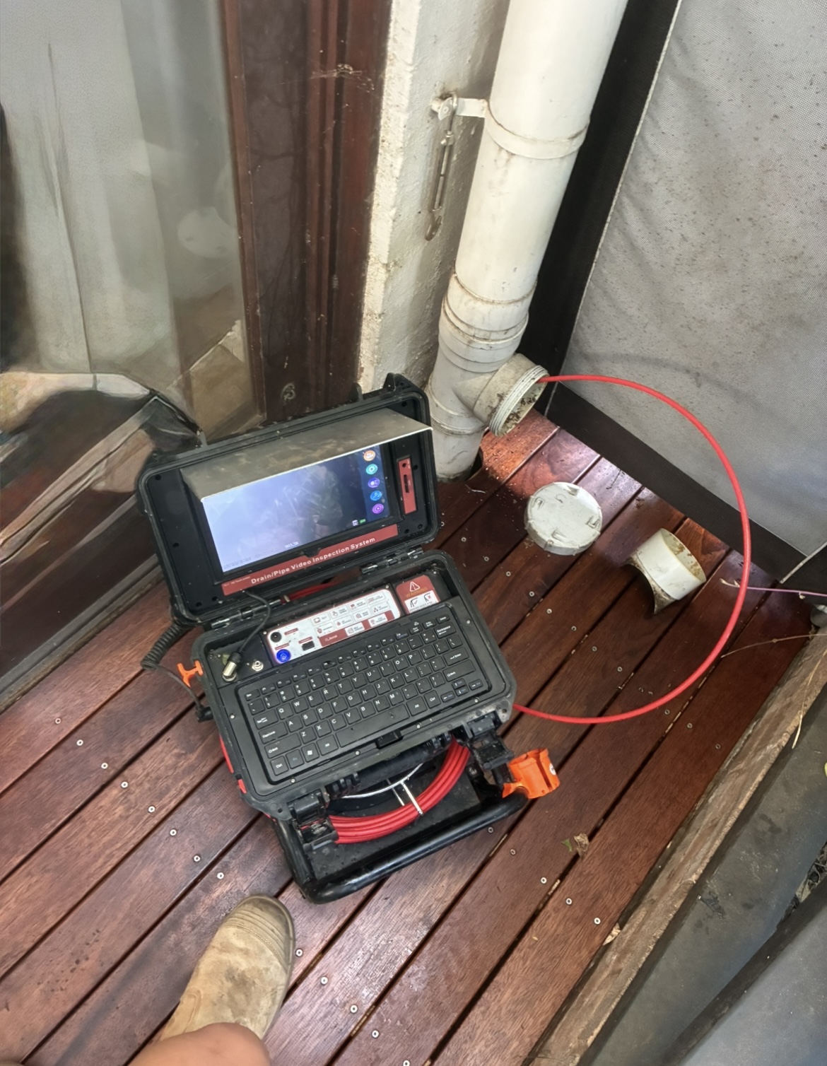 Drain inspection camera kit on a deck next to a PVC drain pipe