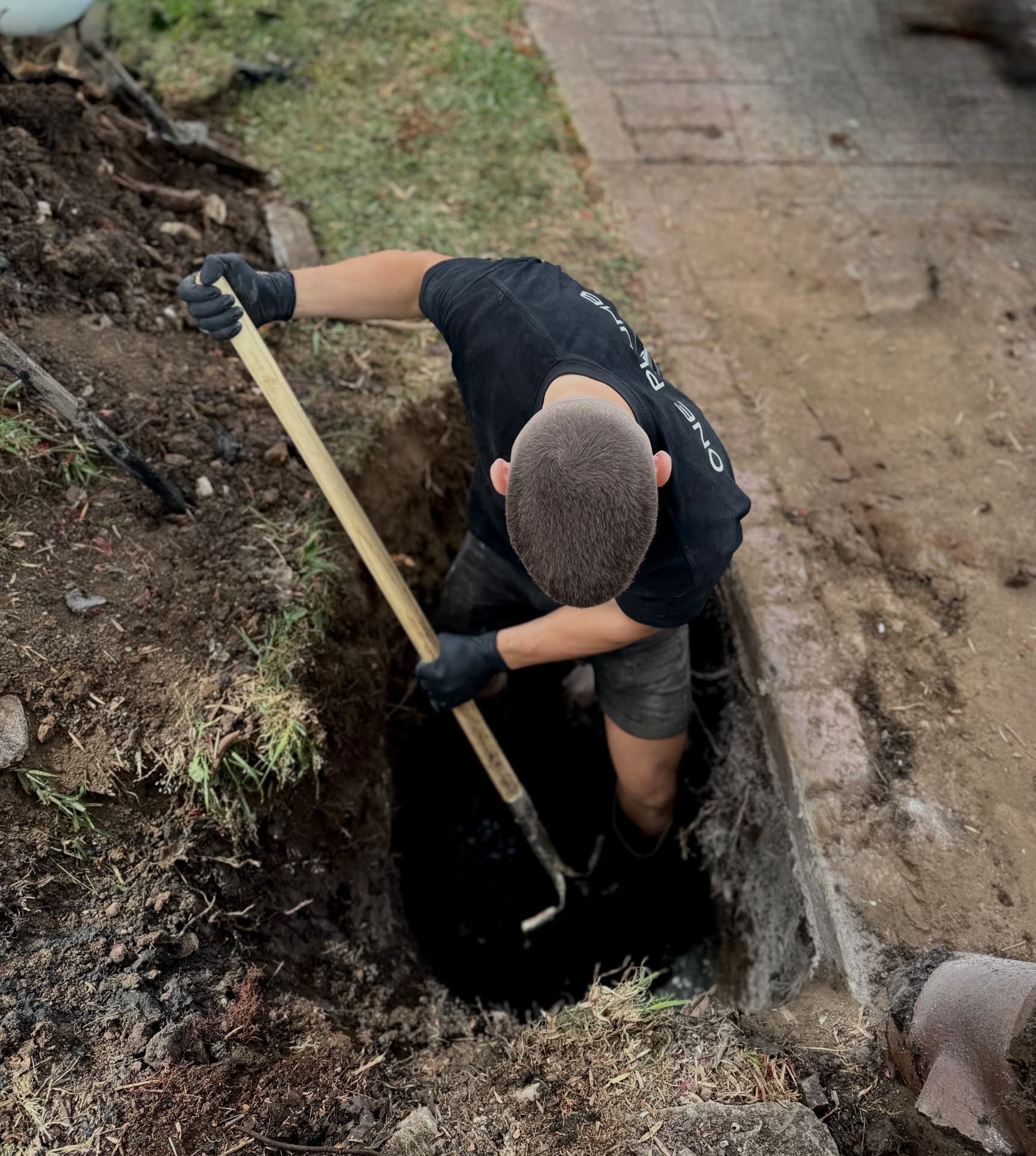 One Plumb digging an open trench on a drainage job